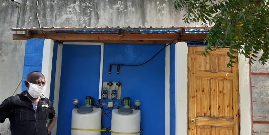hombre delante de infraestructura de agua en Haití